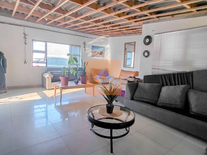 Spacious living area featuring tiled flooring and large windows, currently requiring ceiling completion and finishing works.