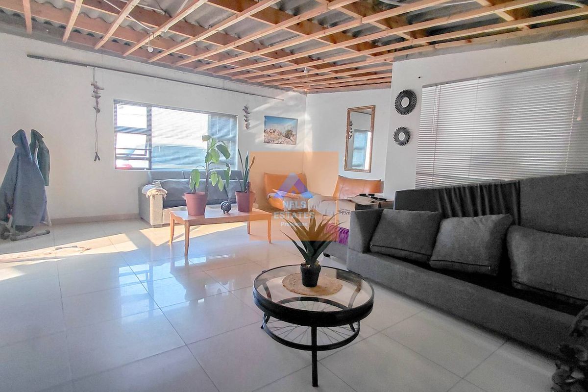 Spacious living area featuring tiled flooring and large windows, currently requiring ceiling completion and finishing works.