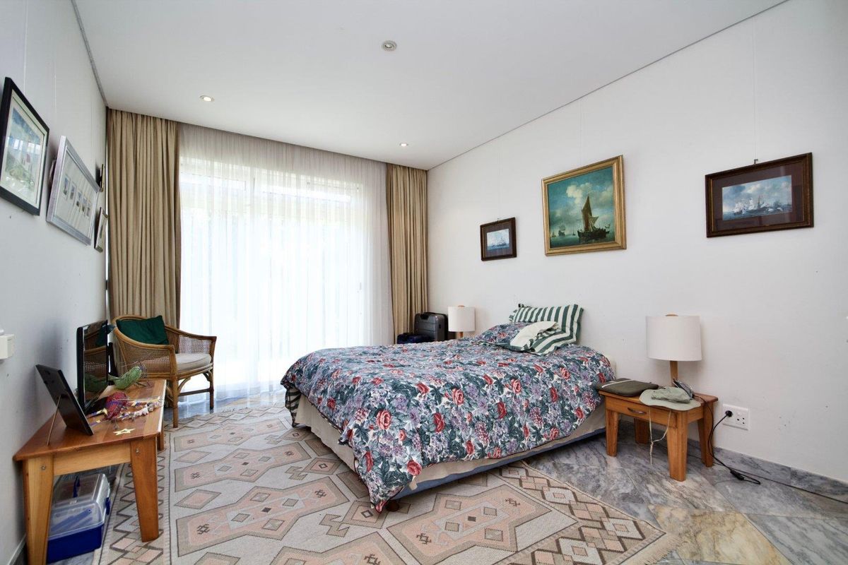 A well-lit bedroom featuring marble flooring, recessed downlighting, and large sliding glass doors that provide access to the exterior.