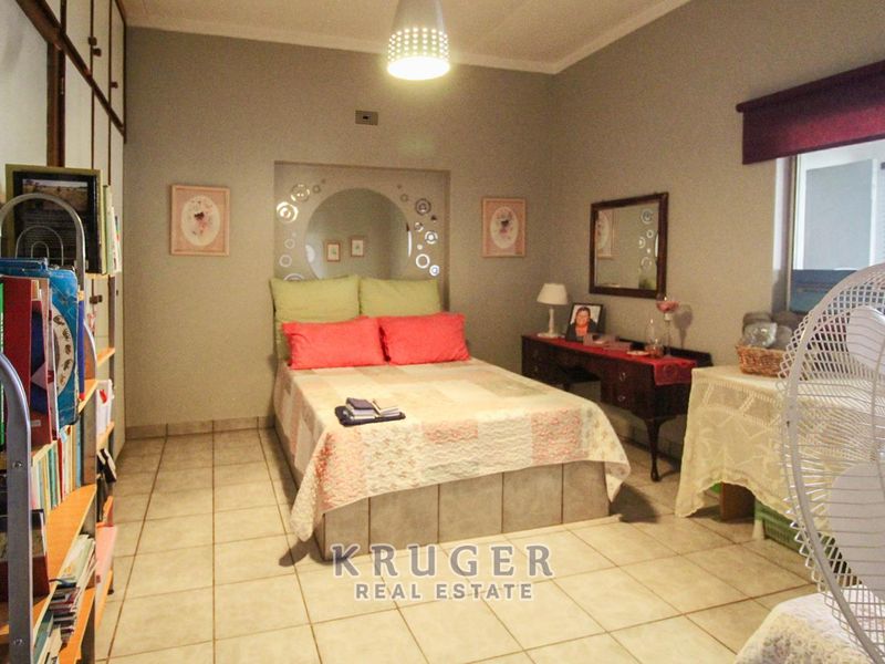 A bedroom featuring tiled flooring, built-in cupboards, and a decorative recessed wall niche behind the bed area.