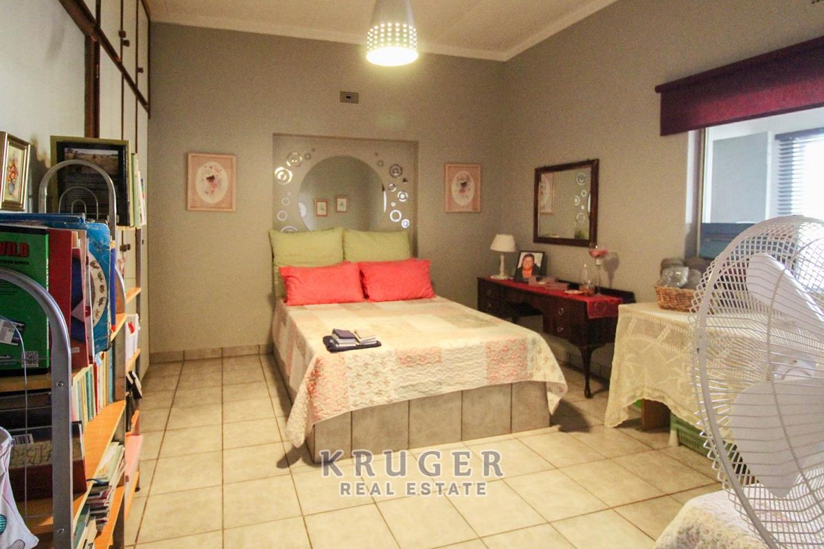 A bedroom featuring tiled flooring, built-in cupboards, and a decorative recessed wall niche behind the bed area.