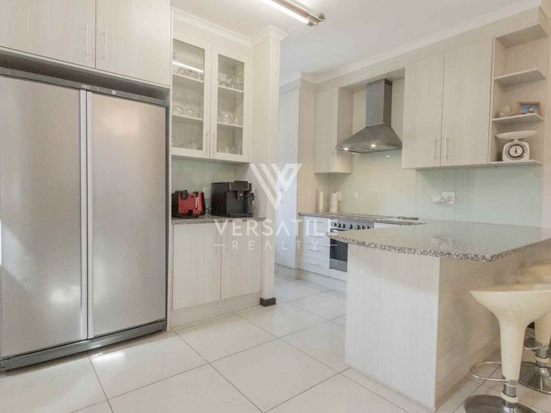 Modern kitchen featuring light-toned cabinetry, granite countertops, stainless steel appliances, and a breakfast bar, offering a clean and functional cooking space.