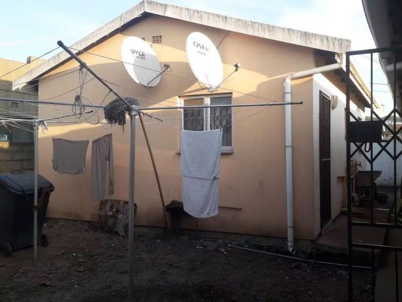 Rear exterior view of the house showing the back facade, security features, and satellite dish installations.