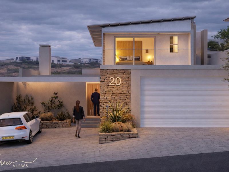 Modern townhouse facade featuring stone cladding, a paved driveway, a sectional garage door, and an upper-level balcony with glass balustrades.