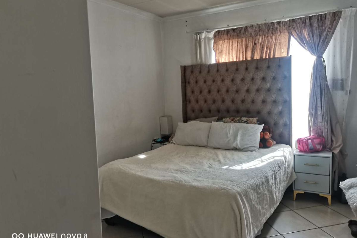 A bedroom featuring tiled flooring and a window with curtain tracks.