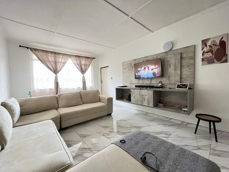 A bright living room featuring modern marble-look floor tiles and a custom built-in floating media console with integrated feature wall paneling.