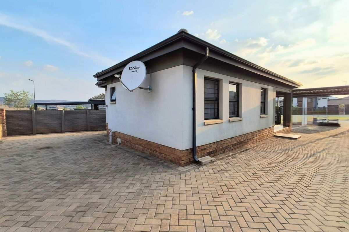 Rear exterior view of the property featuring neat brick paving, a satellite dish, and well-maintained brick and plaster wall finishes.