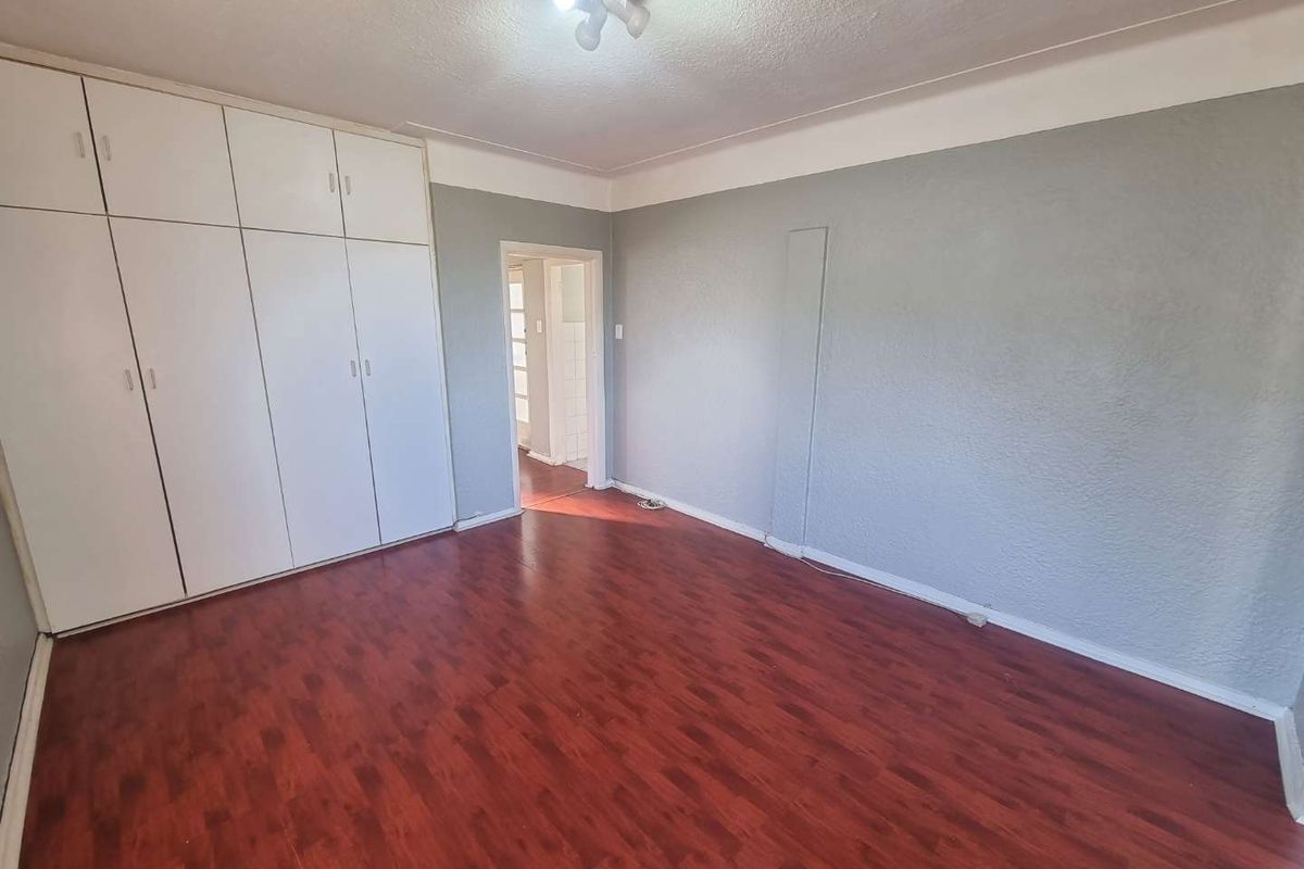 A vacant bedroom featuring laminate flooring and floor-to-ceiling built-in cupboards, offering a neutral canvas for personalization.