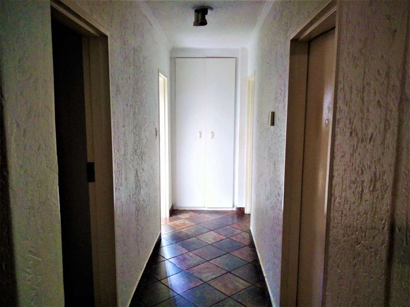 A functional hallway featuring tiled flooring and a built-in storage cupboard, providing access to multiple rooms within the townhouse.