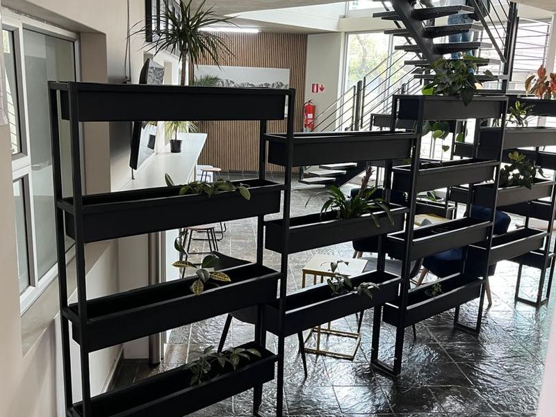 Modern office space featuring a striking metal staircase, tiled flooring, and integrated lighting, creating an open and professional work environment.