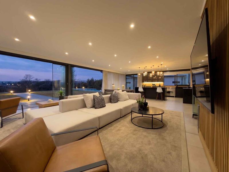 Spacious open-plan living and kitchen area featuring modern cabinetry, recessed lighting, and expansive sliding glass doors opening to an outdoor view.