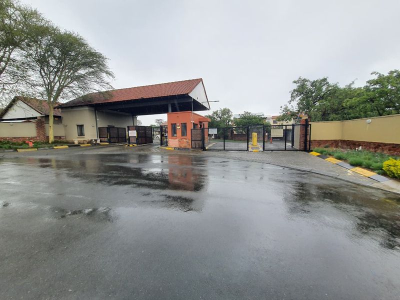 The property features a secure gated entrance with a guard house, paved driveway, and perimeter walling.