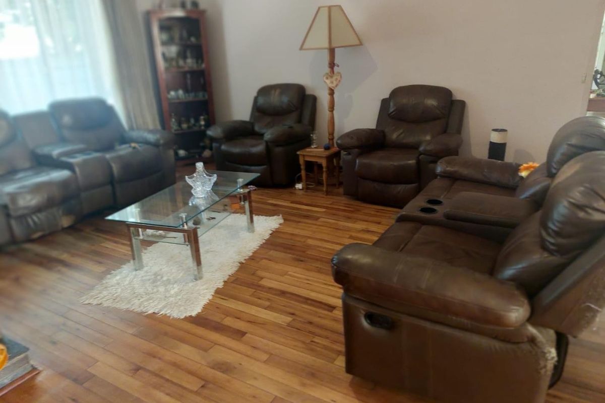 A spacious living room featuring warm-toned hardwood flooring and large windows, providing a comfortable and inviting area for relaxation.