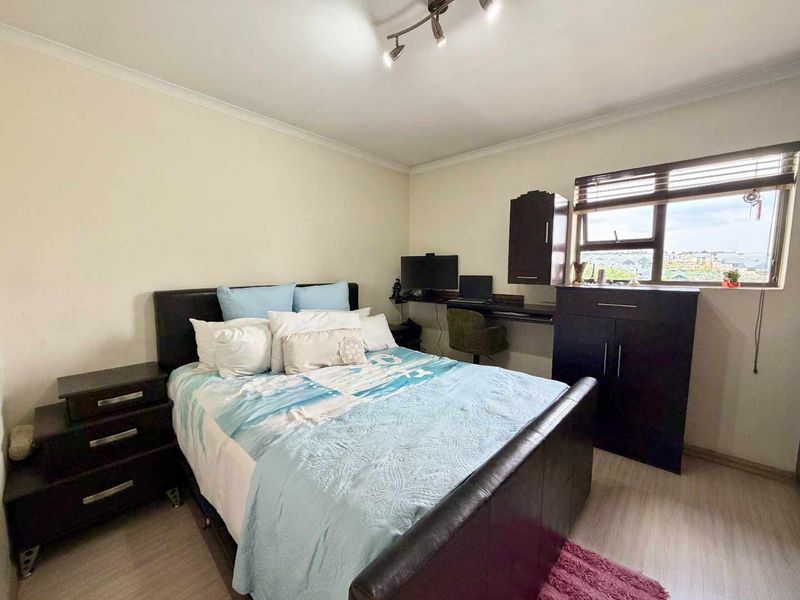 A functional bedroom featuring laminate flooring, built-in desk space, and integrated cabinetry, offering a practical layout with natural light from the window.