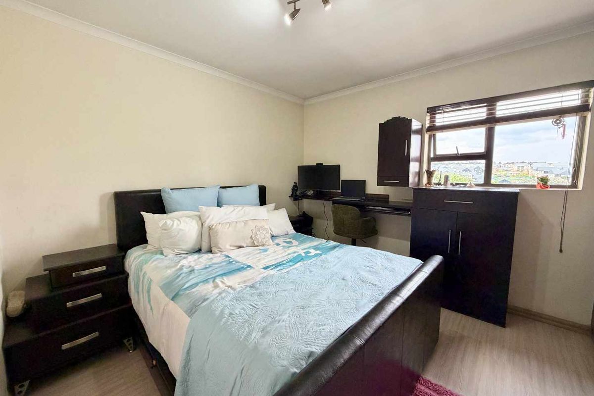 A functional bedroom featuring laminate flooring, built-in desk space, and integrated cabinetry, offering a practical layout with natural light from the window.