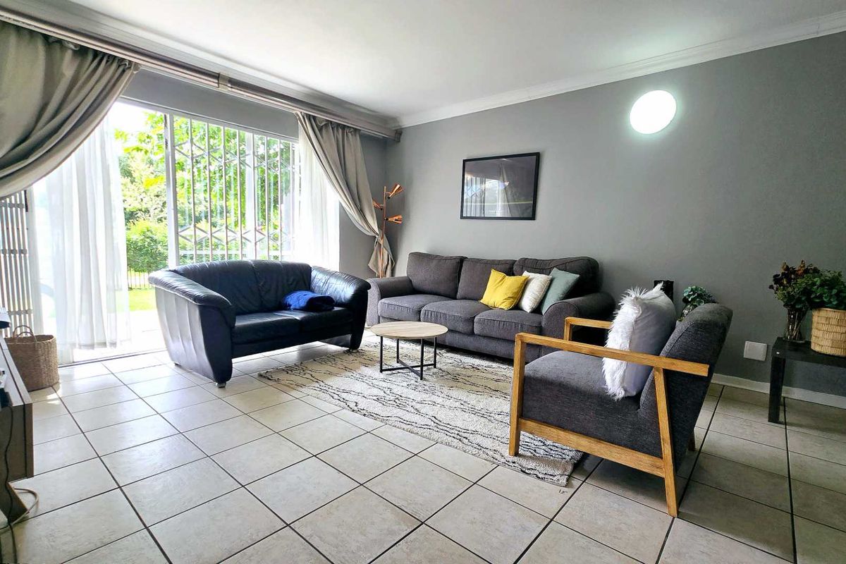 Spacious living room featuring large sliding glass doors with security bars, tiled flooring, and neutral wall finishes, providing direct access to the outdoor area.