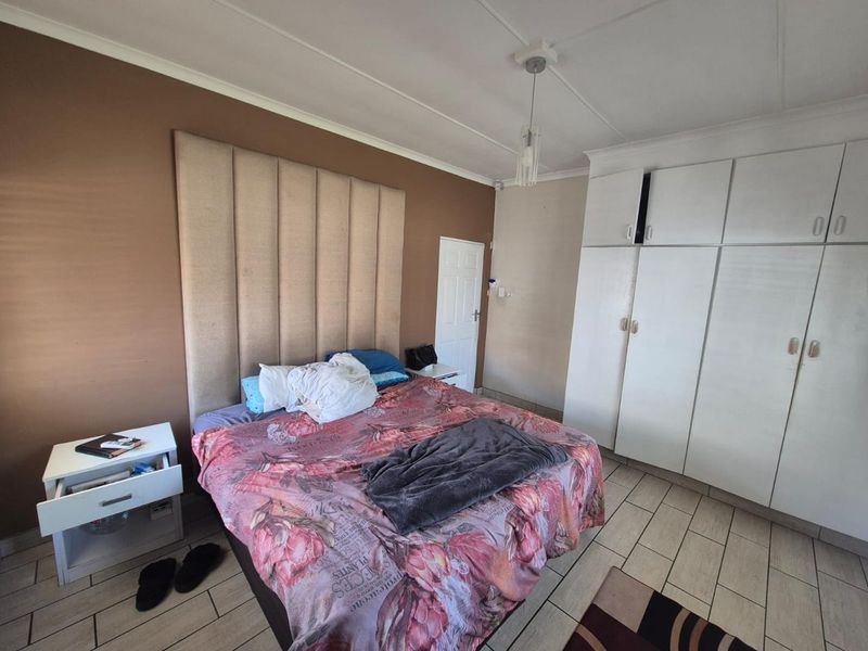 A bedroom featuring tiled flooring, built-in cupboards for storage, and a central pendant light fixture.