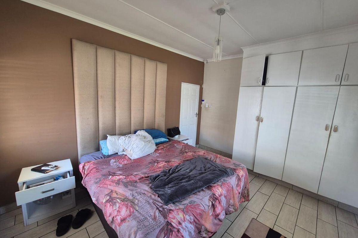 A bedroom featuring tiled flooring, built-in cupboards for storage, and a central pendant light fixture.