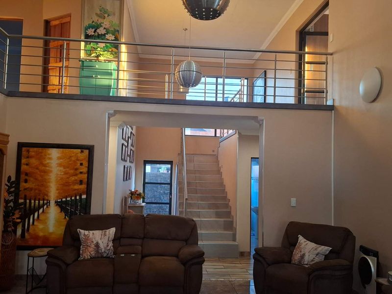 Spacious living area featuring a mezzanine level with a modern stainless steel balustrade and an open staircase leading to the upper floor.