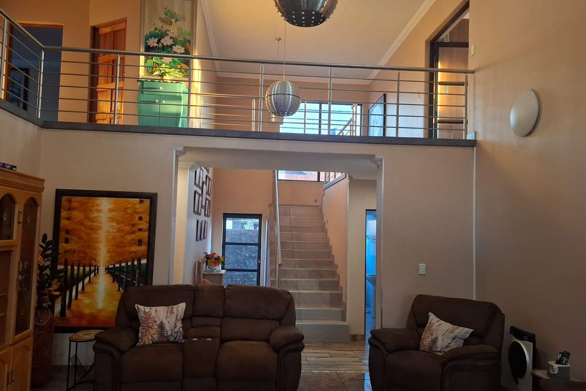 Spacious living area featuring a mezzanine level with a modern stainless steel balustrade and an open staircase leading to the upper floor.