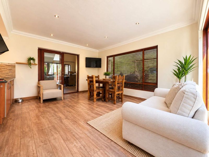 Bright open-plan living area featuring laminate flooring, recessed lighting, and large timber-framed windows and sliding doors leading to the exterior.