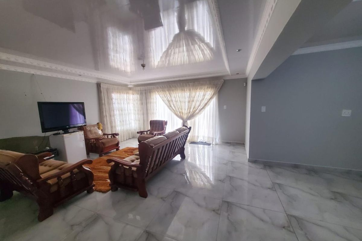 Spacious living area featuring high-gloss ceiling finish, large format marble-look floor tiles, and sliding glass doors leading to the exterior.