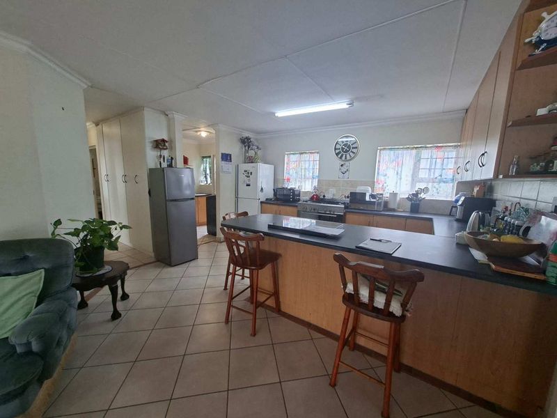 Open plan kitchen and living area featuring a central island, tiled flooring, and wooden cabinetry, offering a functional layout for daily living.