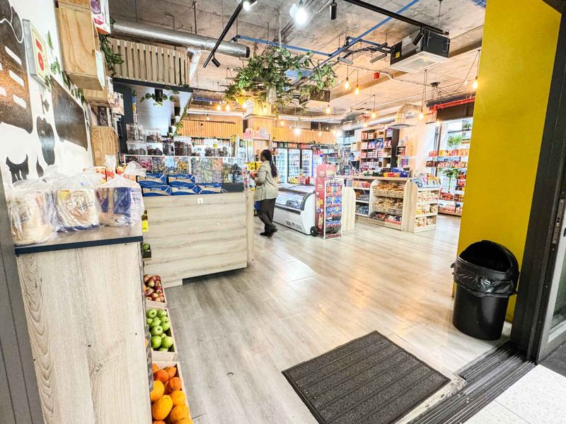 A well-lit retail space featuring an open-plan layout with exposed industrial ceilings, laminate flooring, and integrated shelving units for product display.