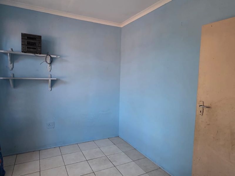 A simple bedroom featuring tiled flooring and light blue walls, offering a blank canvas for potential interior design updates.