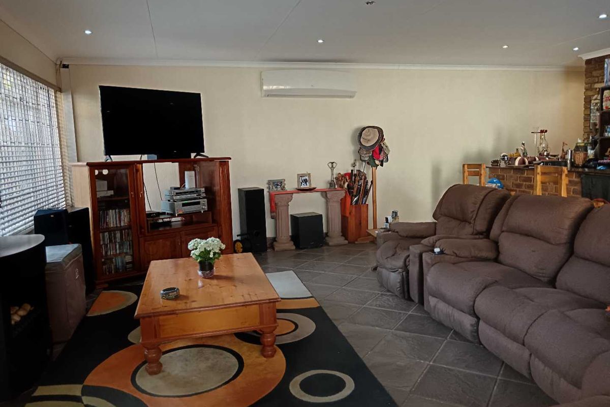 Spacious living area featuring tiled flooring, recessed downlighting, and a wall-mounted air conditioning unit.