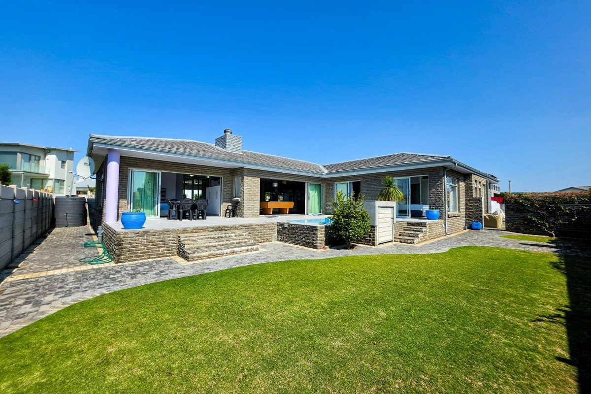 Rear view of the property featuring a brick facade, paved patio area, swimming pool, and a well-maintained lawn.