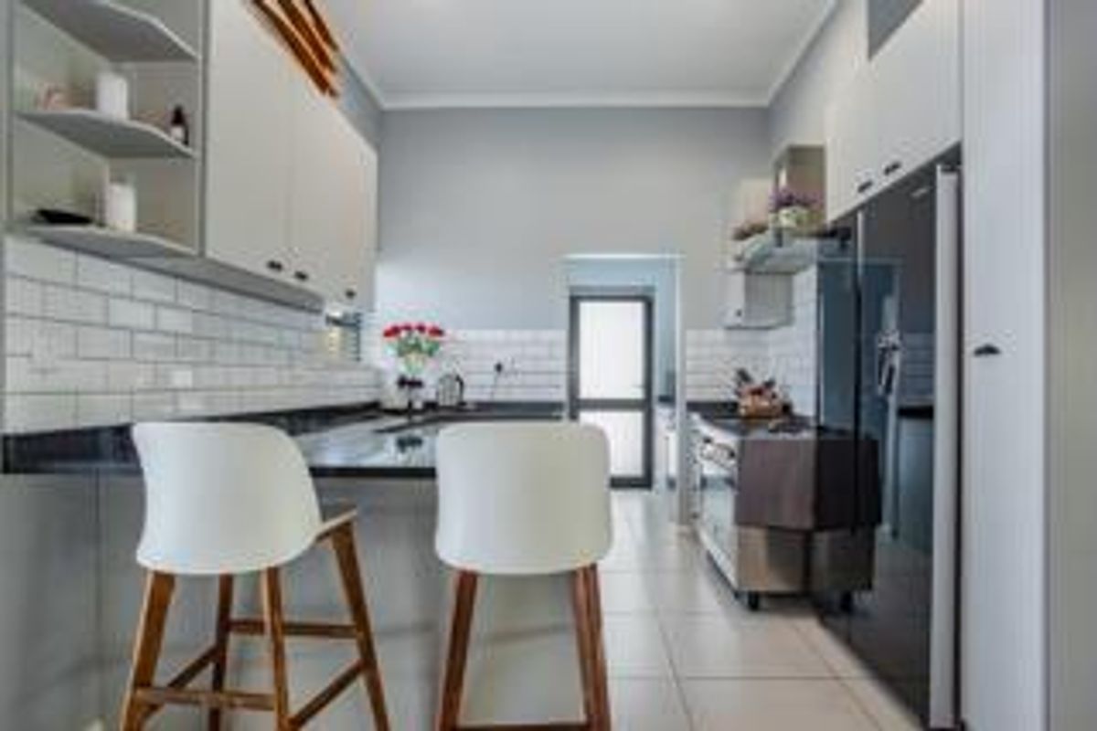 Modern kitchen featuring white cabinetry, subway tile backsplash, dark stone countertops, and a breakfast bar area with tiled flooring.