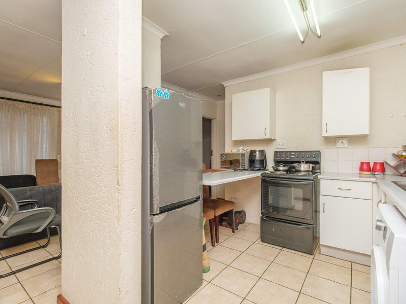 A functional kitchen area featuring tiled flooring, built-in cabinetry, and a freestanding stove, adjacent to the main living space.
