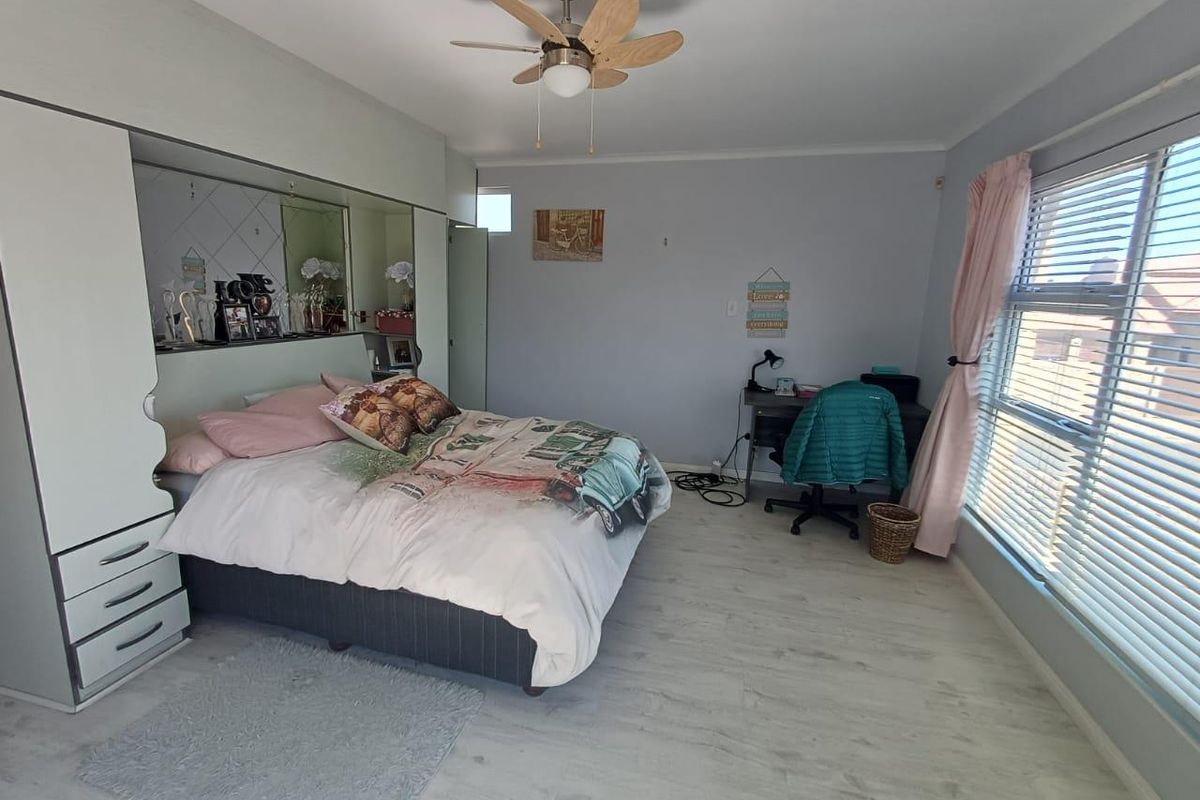 Spacious bedroom featuring built-in cabinetry, a ceiling fan, and large windows with blinds, offering a bright and functional living space.