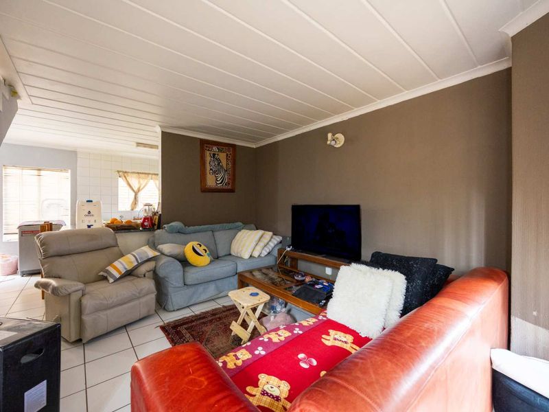 Open plan living area featuring tiled flooring and a tongue and groove ceiling, seamlessly connecting to the kitchen space.