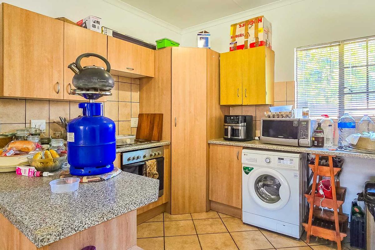 A functional kitchen featuring laminate cabinetry, granite countertops, tiled backsplash, and a built-in oven with space for a washing machine.