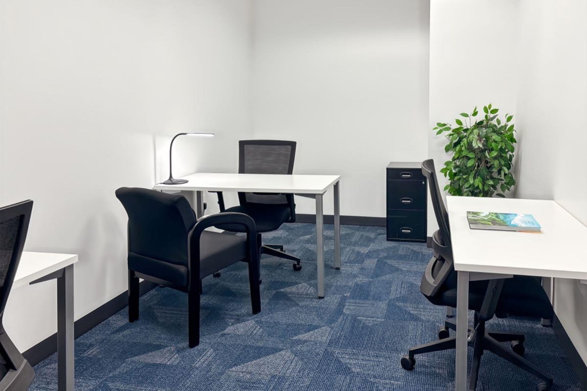 A clean and functional office space featuring patterned carpet flooring and neutral wall finishes, suitable for a professional work environment.