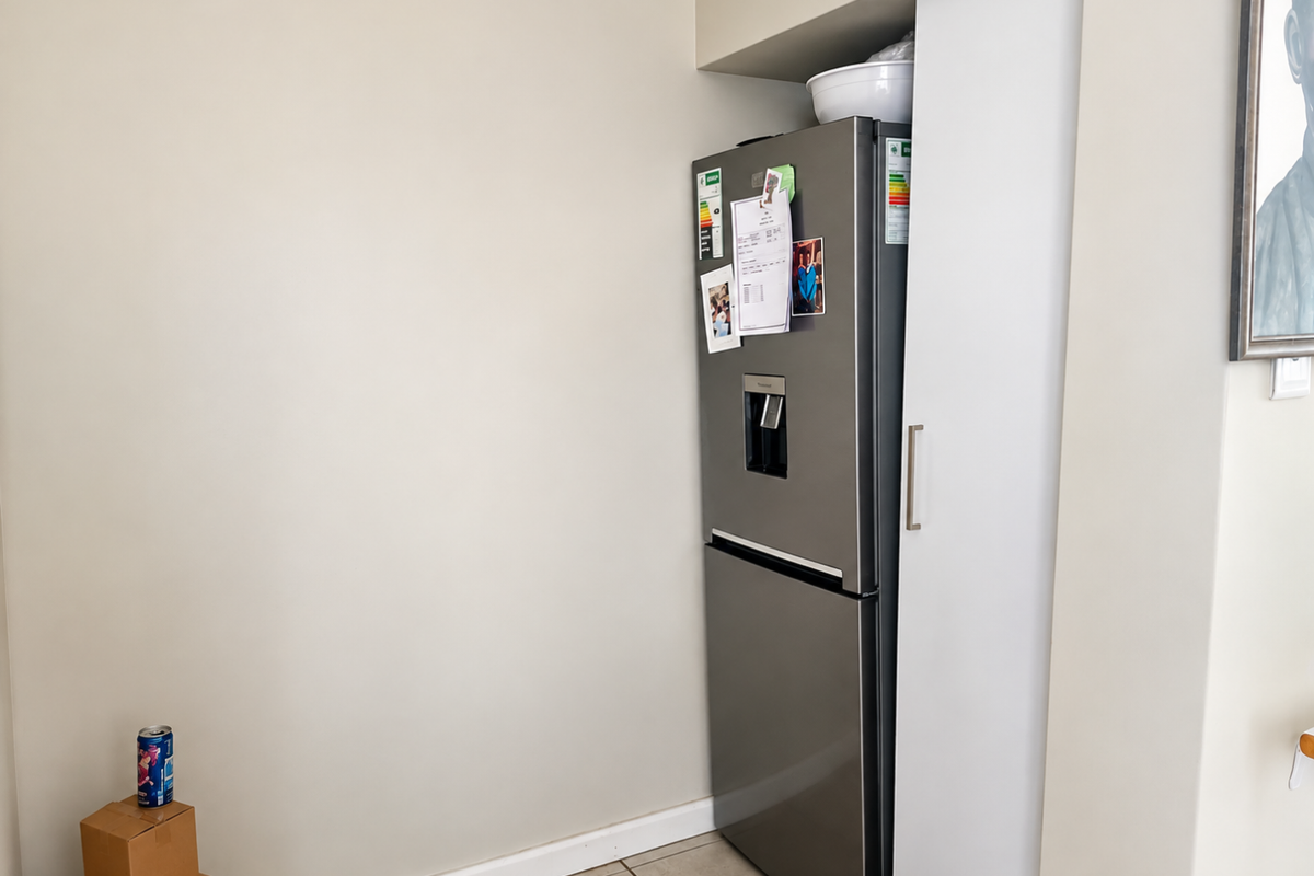 A kitchen corner featuring a built-in pantry cupboard with a sleek white finish and tiled flooring.