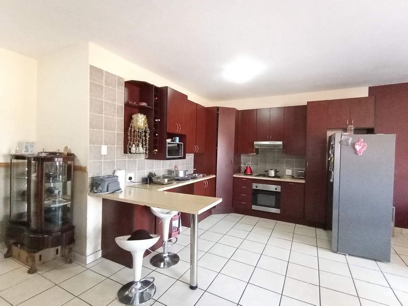A functional kitchen featuring dark wood cabinetry, a breakfast bar, tiled flooring, and built-in appliances, offering a practical layout for daily cooking and dining.