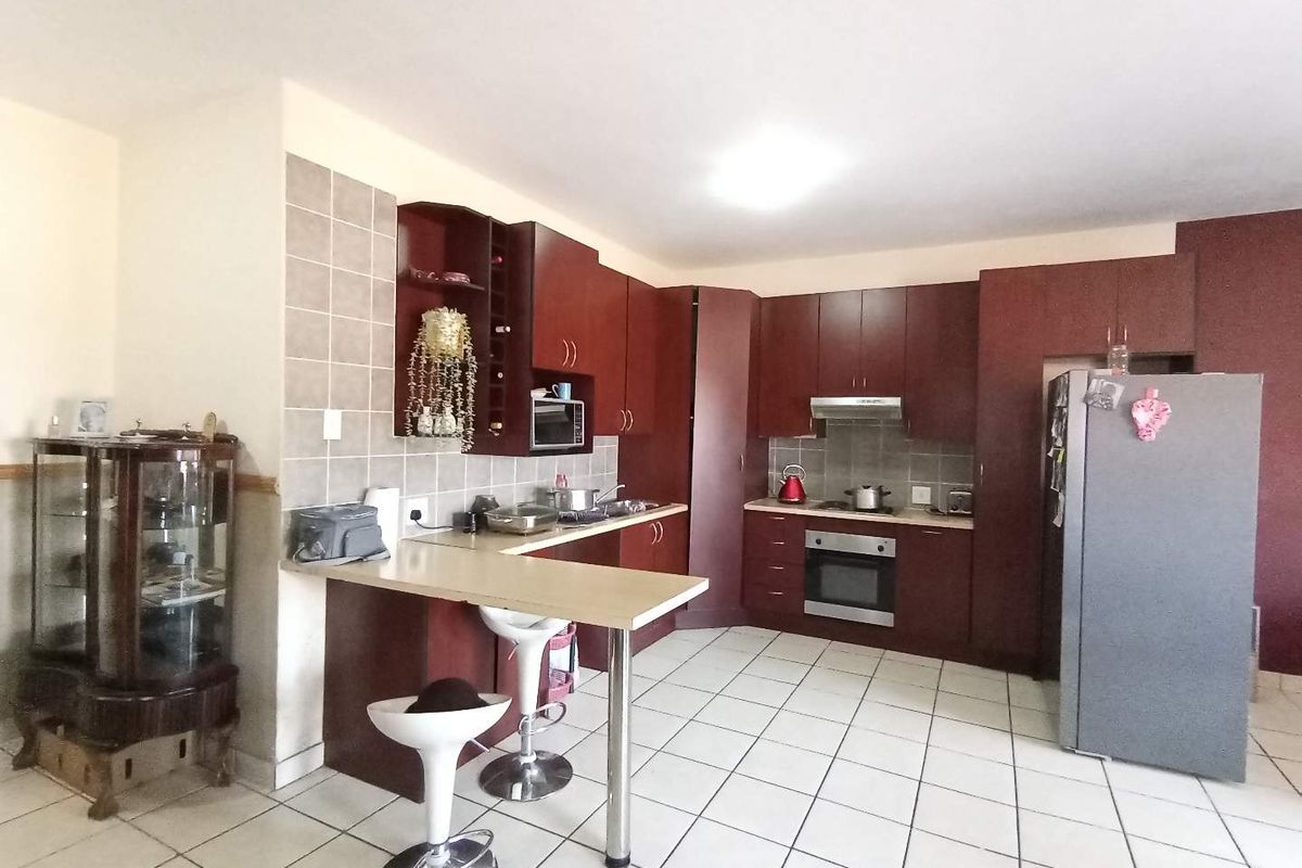 A functional kitchen featuring dark wood cabinetry, a breakfast bar, tiled flooring, and built-in appliances, offering a practical layout for daily cooking and dining.