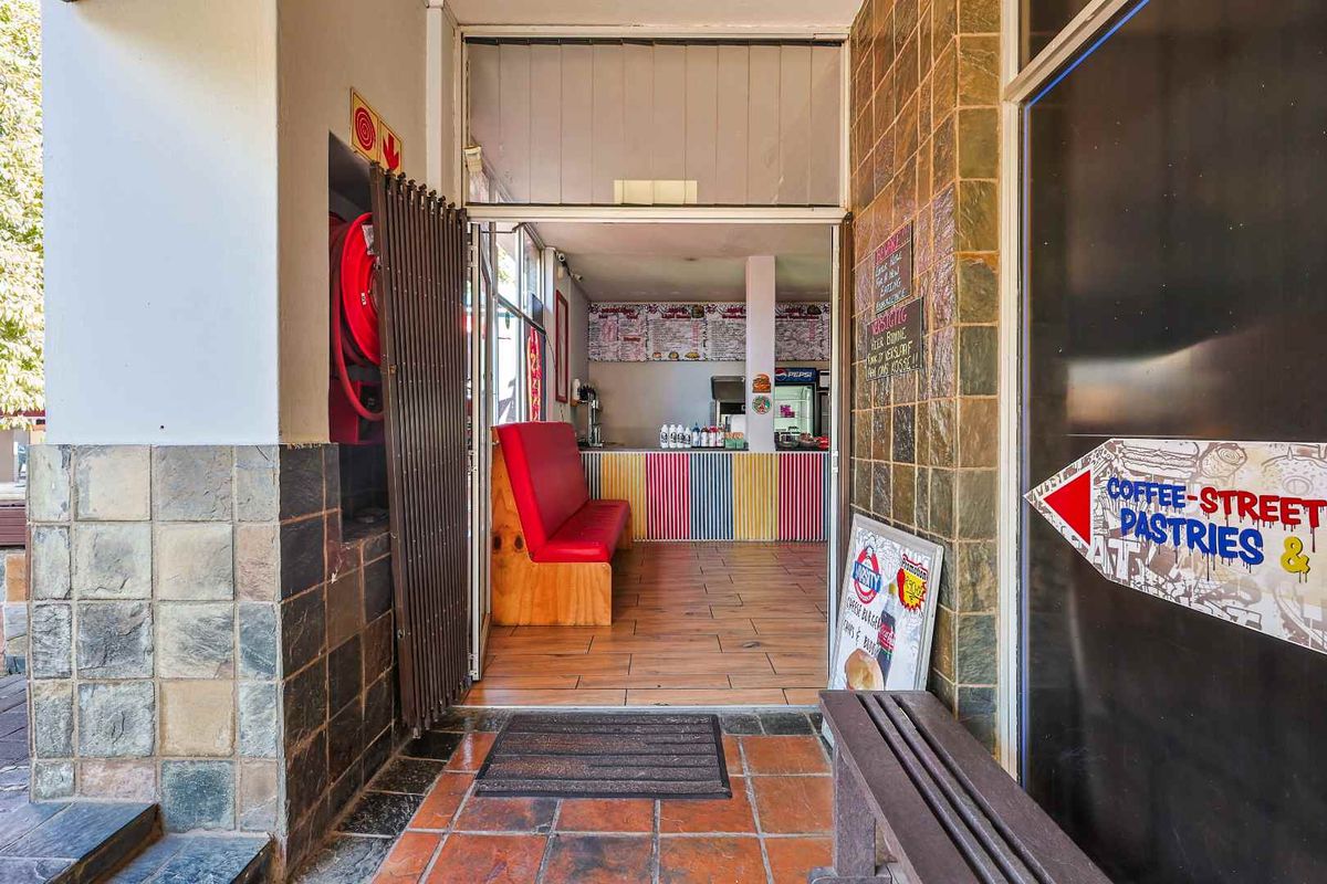 Entrance area of a commercial property featuring stone wall cladding, tiled flooring, and a security gate leading into the main service space.