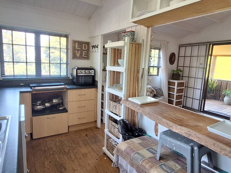 Compact kitchen featuring timber cabinetry, laminate countertops, and a breakfast bar, with direct access to an outdoor deck area.