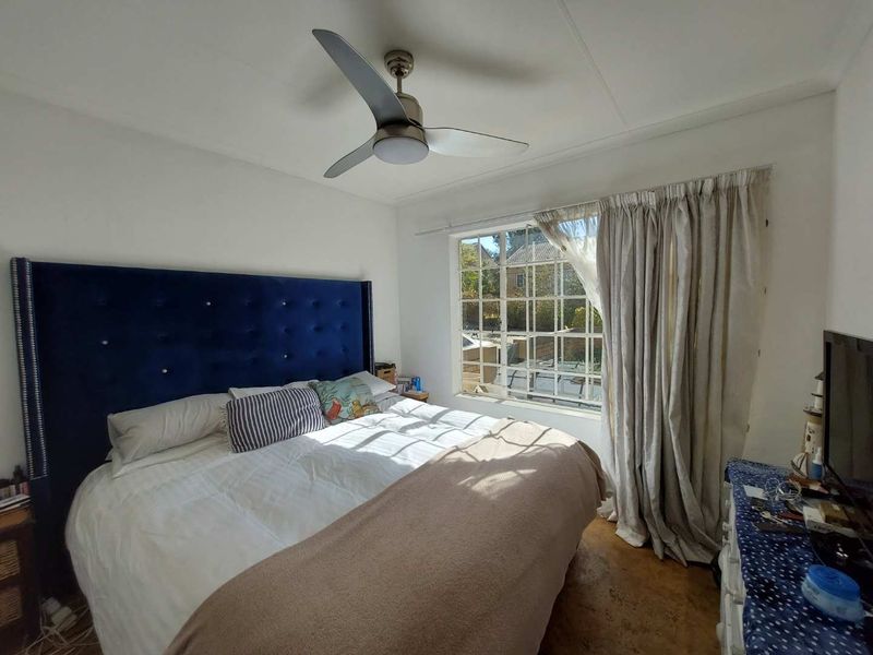 A bedroom featuring a ceiling fan and a large grid-pattern window that allows natural light into the space.
