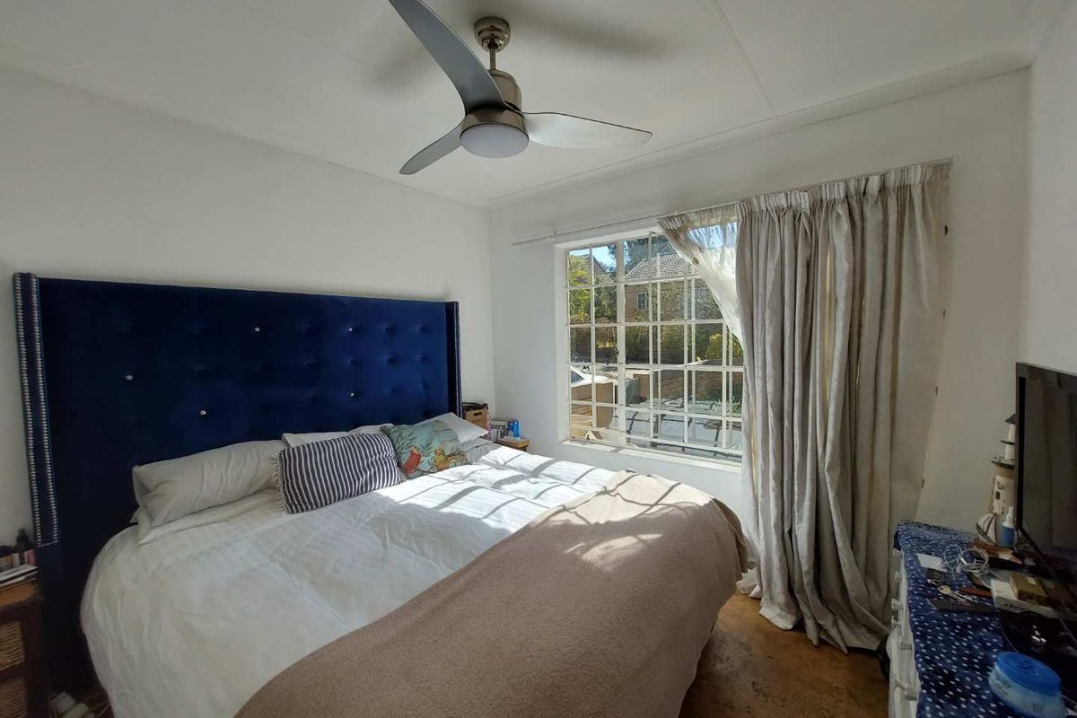 A bedroom featuring a ceiling fan and a large grid-pattern window that allows natural light into the space.