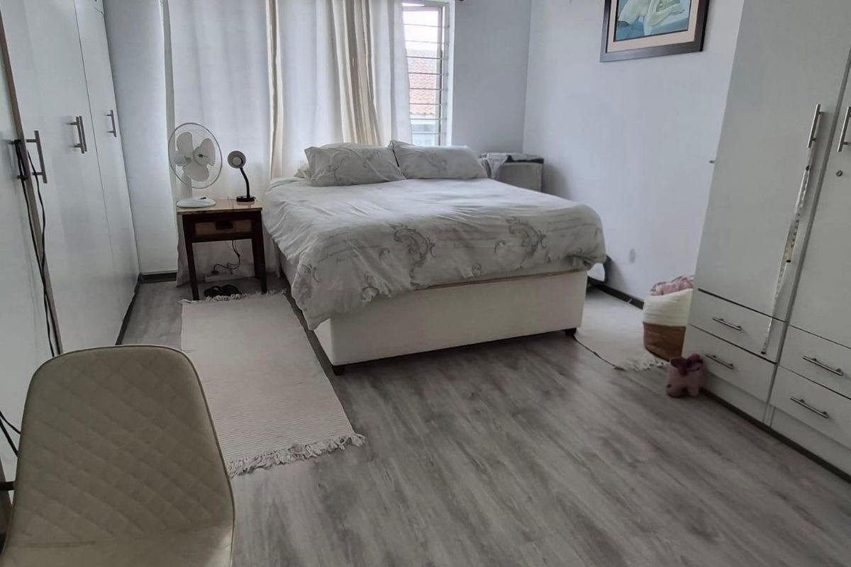 A functional bedroom featuring light-toned laminate flooring and ample built-in cupboard storage space.