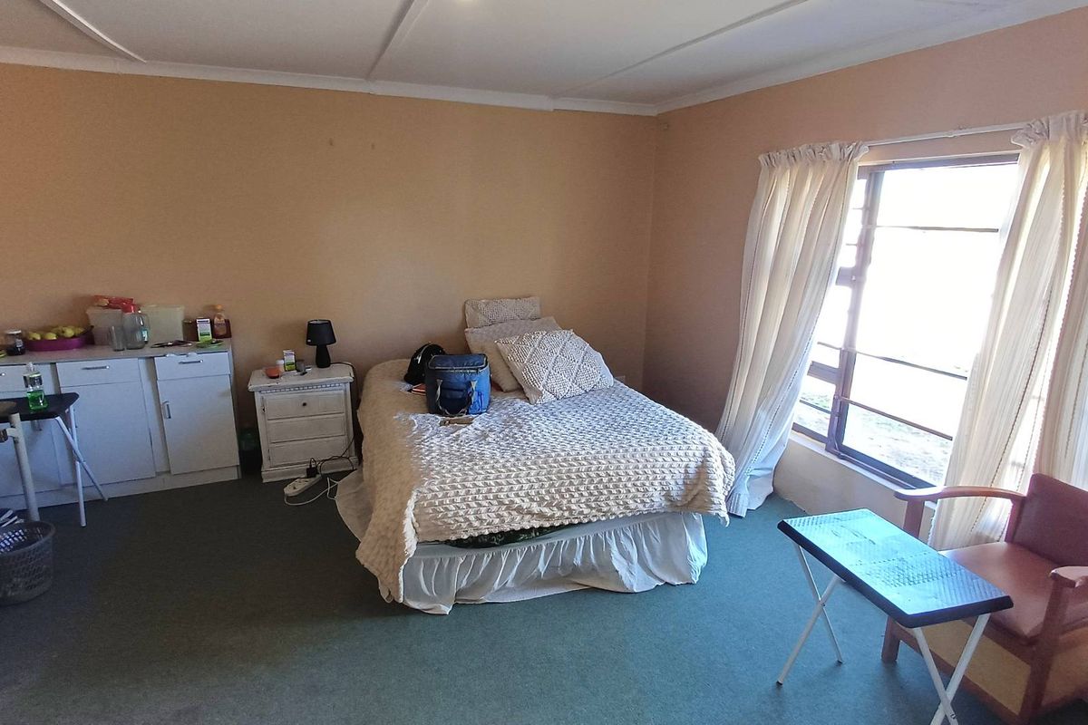 A bedroom featuring built-in cabinetry, large windows with natural light, and carpeted flooring, offering a functional space ready for cosmetic updates.