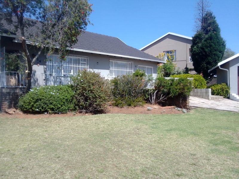 Front view of the house featuring a tiled roof, security bars on windows, and a well-maintained front garden with a paved driveway.