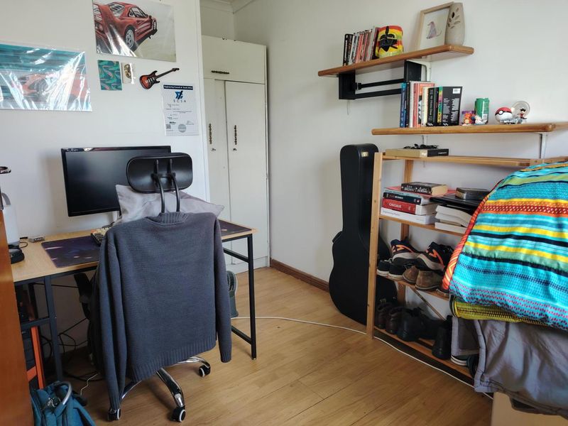 A bedroom featuring laminate flooring and a built-in wardrobe, currently utilized as a home office and study space.