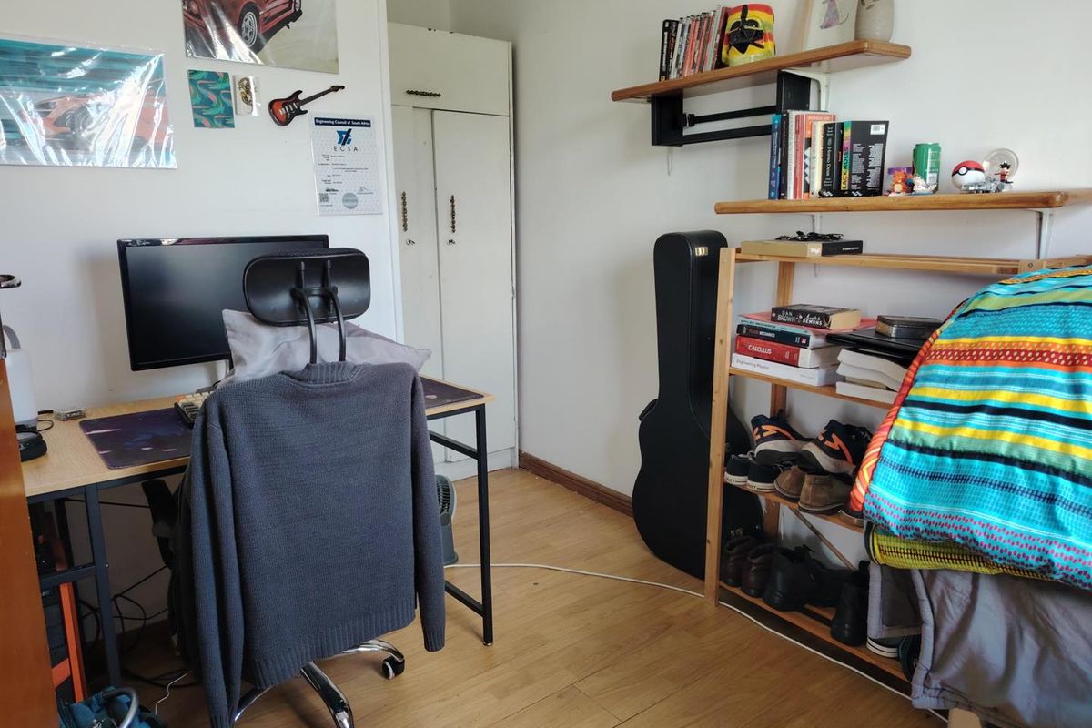 A bedroom featuring laminate flooring and a built-in wardrobe, currently utilized as a home office and study space.