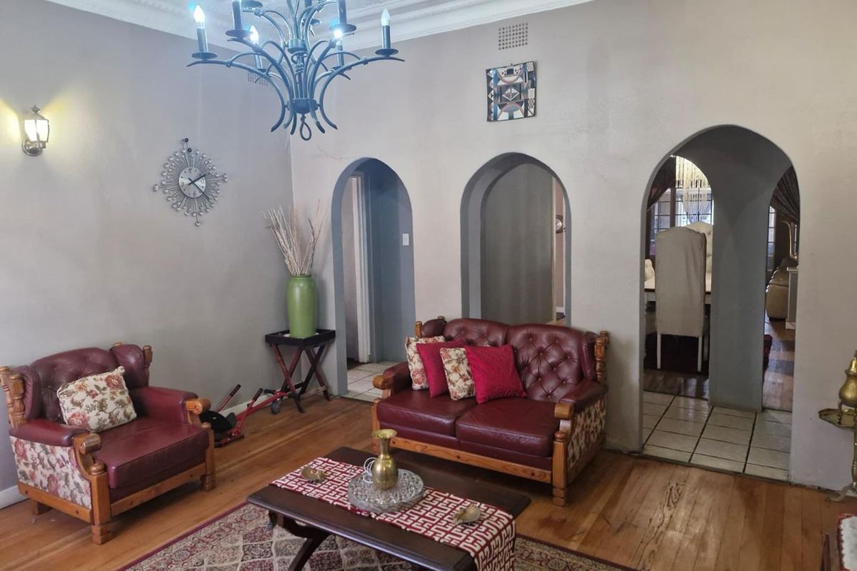 A living room featuring hardwood flooring, decorative ceiling cornices, and distinctive arched doorways leading to adjacent spaces.